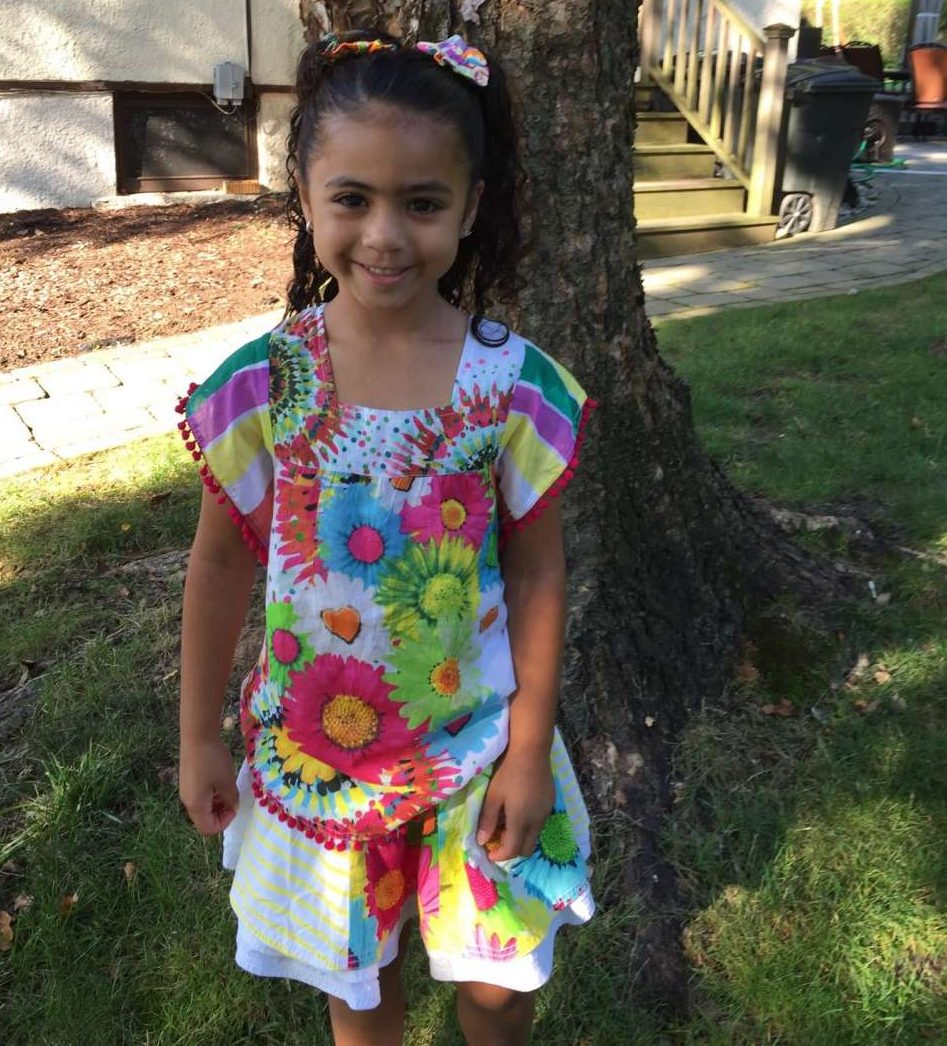 Girl in backyard with Desigual kids printed sunflower tshirt with pom pom trim on sleeves