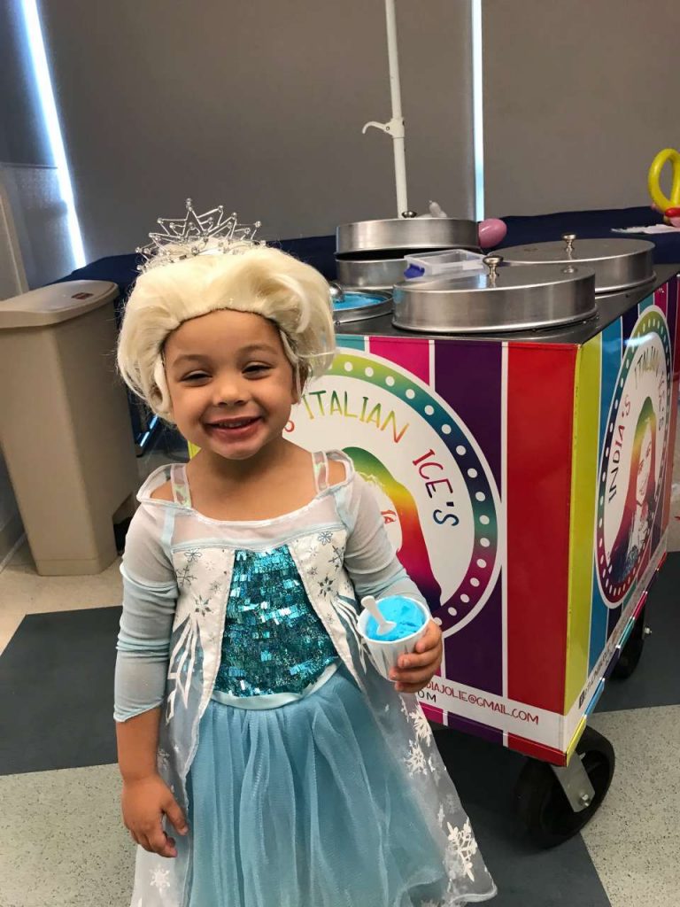 girl in elsa costume eating blue italian ice