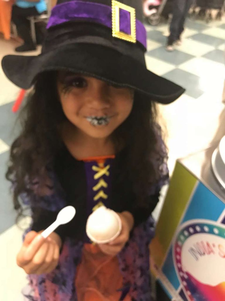 Girl eating lemon Italian ice in a witch costume