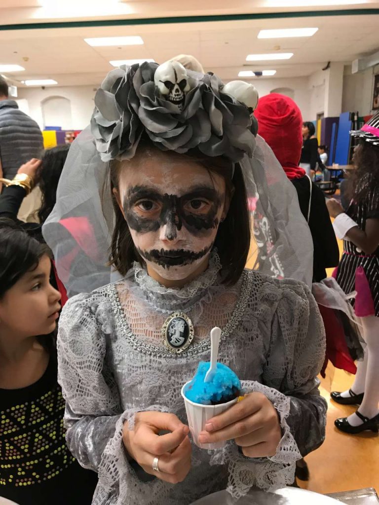 girl dressed in day of the dead grey bride costume eating blue italian ice
