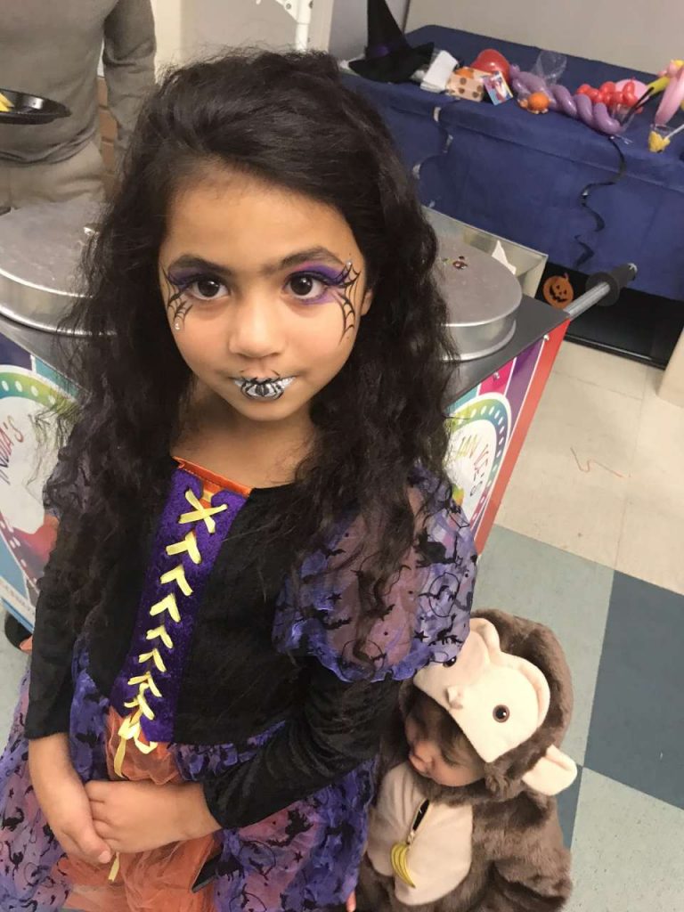 girl with witch costume and facepaint in front of italian ice cart